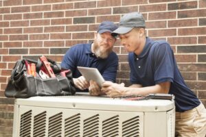 two-technicians-standing-over-outside-ac-unit